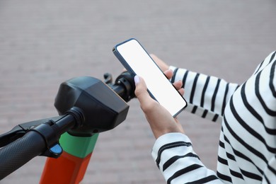 Woman using smartphone to pay and unblock electric kick scooter outdoors, closeup