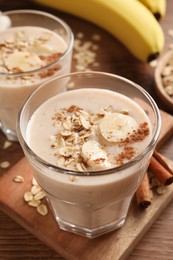 Photo of Tasty banana smoothie with oatmeal and cinnamon on wooden table