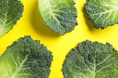 Photo of Fresh savoy cabbage leaves on yellow background, flat lay