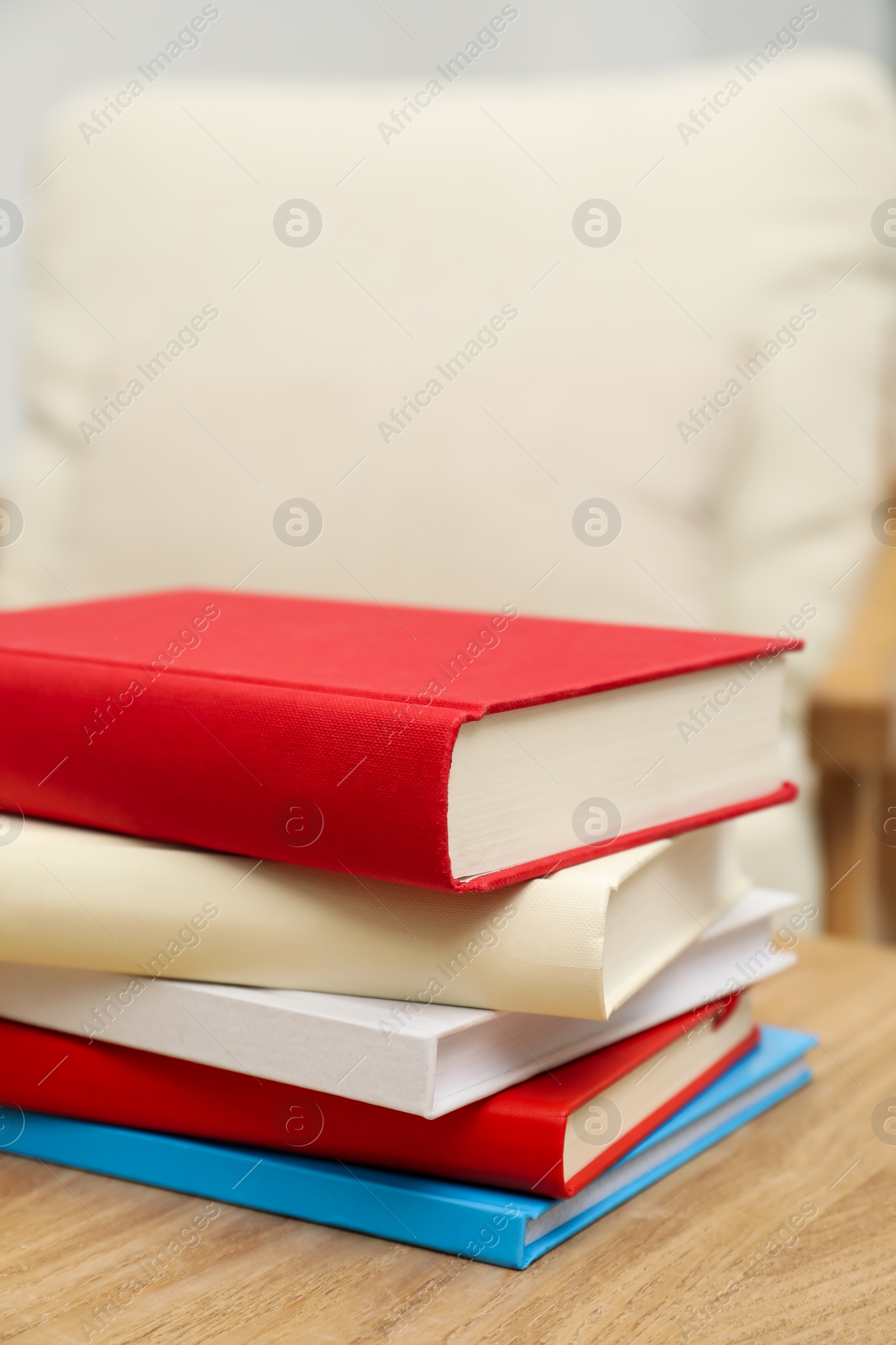 Photo of Stack of hardcover books on wooden table indoors, closeup