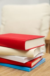 Photo of Stack of hardcover books on wooden table indoors, closeup