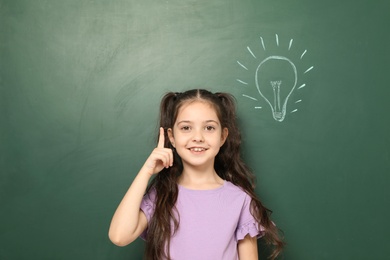 Photo of Little school child near chalkboard with lightbulb drawing