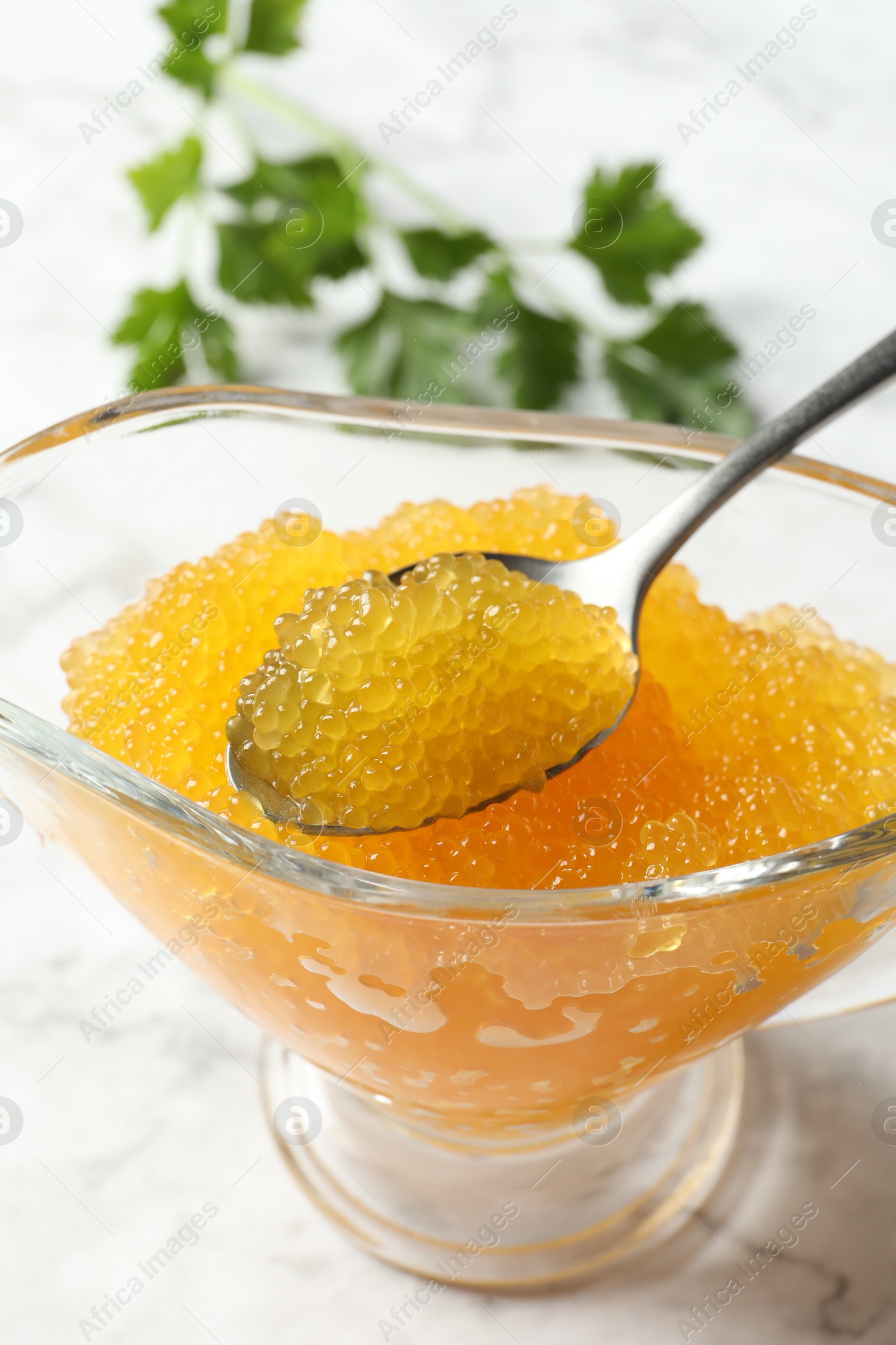 Photo of Fresh pike caviar in gravy boat and spoon on white marble table, closeup