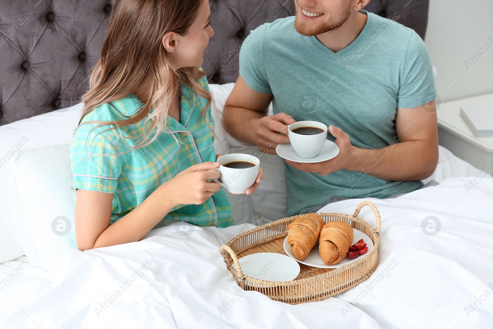 Photo of Happy young couple having romantic breakfast in bed at home