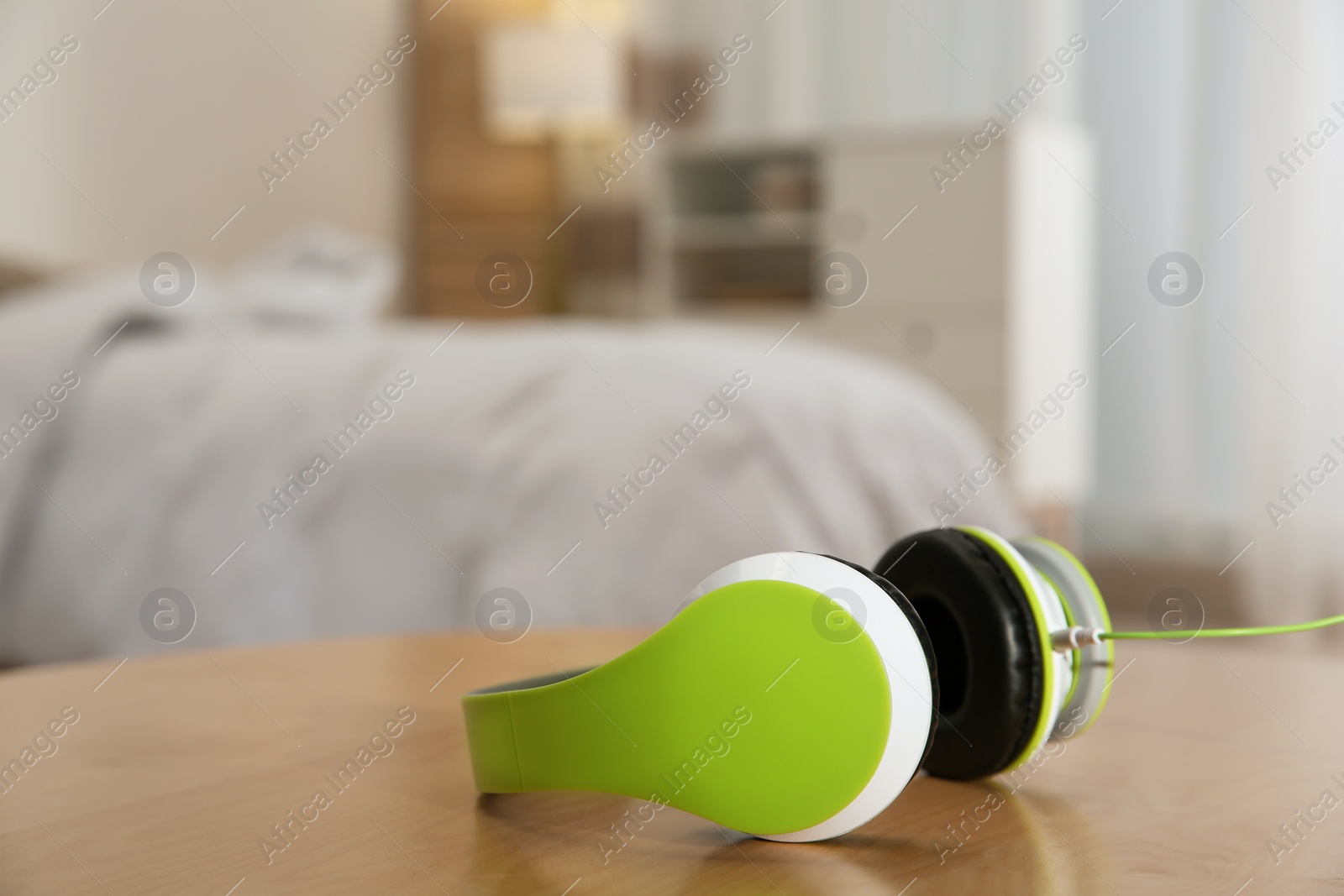 Photo of Stylish modern headphones with earmuffs on table against blurred background, space for text