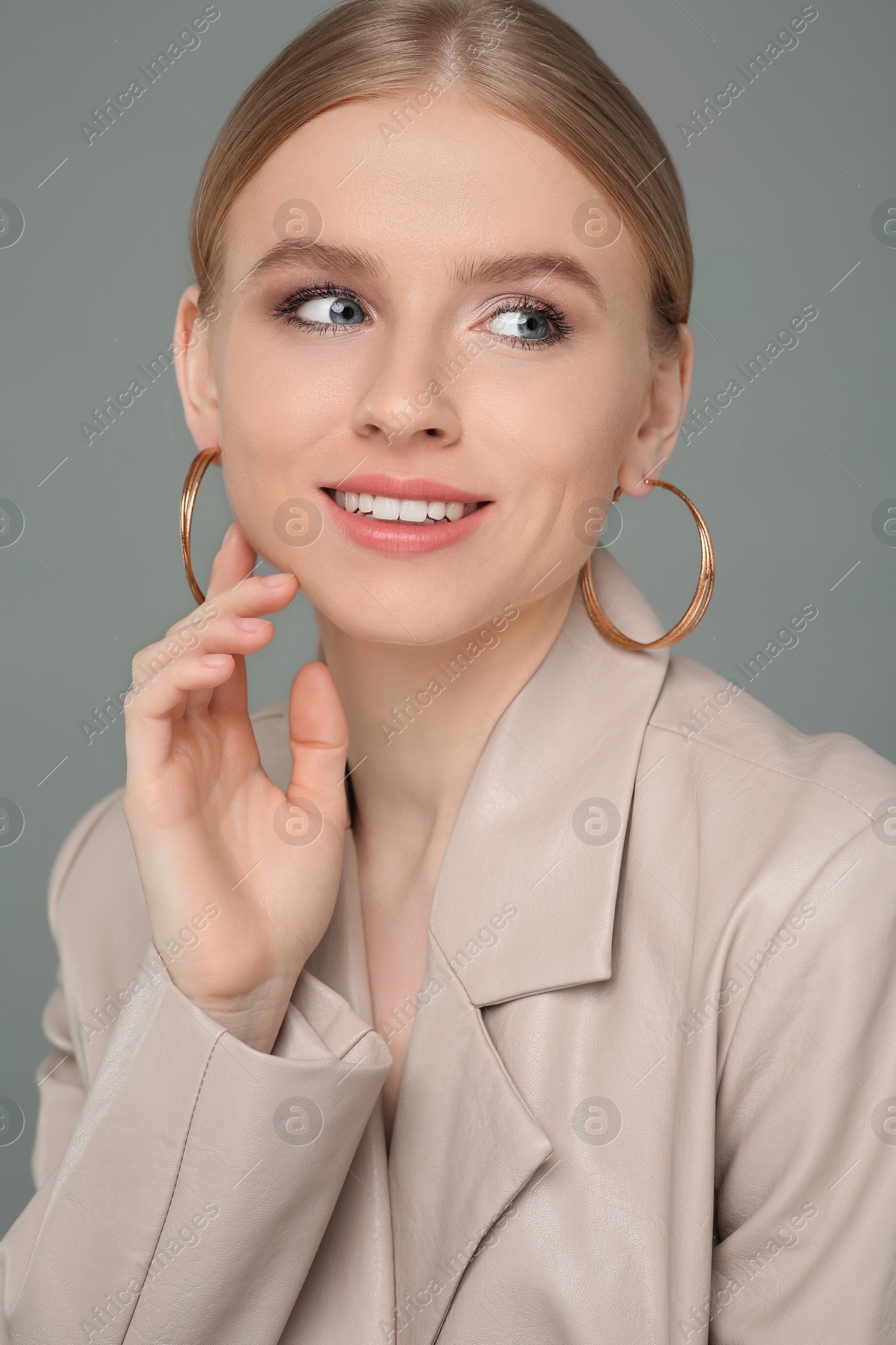 Photo of Beautiful young woman with elegant earrings on gray background