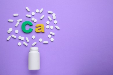 Photo of Symbol Ca (Calcium), medical bottle and pills on violet background, top view. Space for text