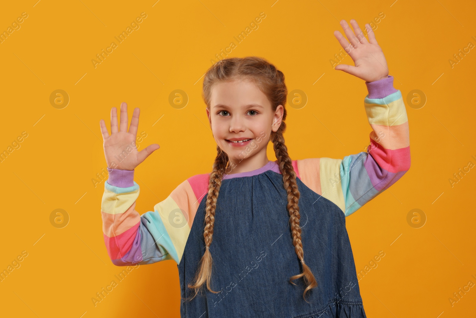 Photo of Happy girl giving high five with both hands on orange background