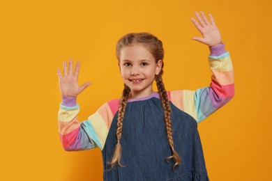 Happy girl giving high five with both hands on orange background