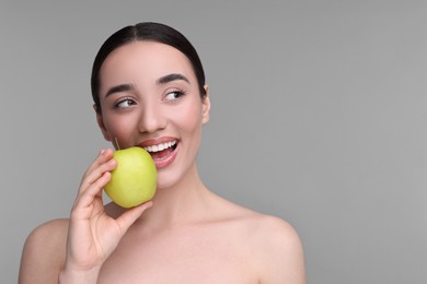 Photo of Beautiful young woman with apple on grey background. Space for text
