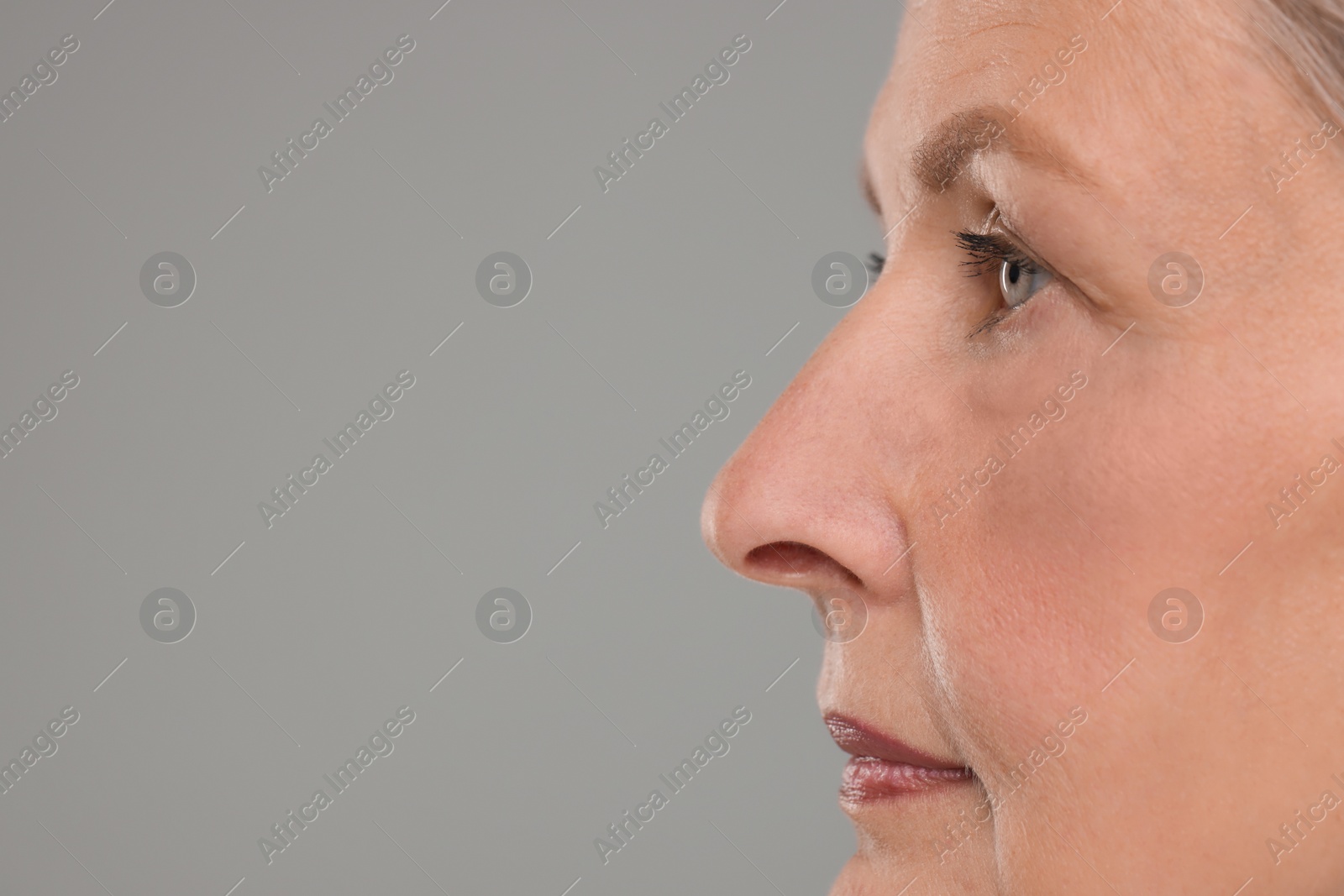 Photo of Senior woman with aging skin on grey background, closeup and space for text. Rejuvenation treatment