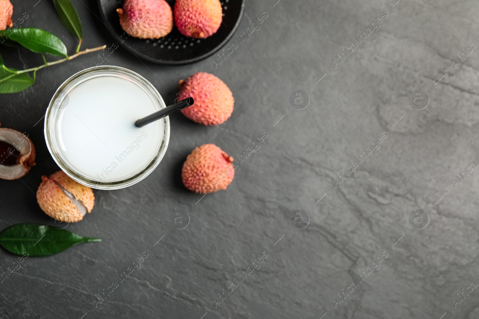 Photo of Fresh lychee juice and fruits on grey table, flat lay. Space for text