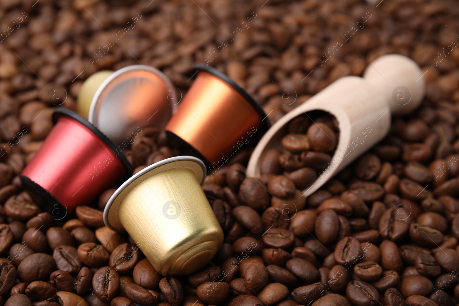 Photo of Many different coffee capsules and scoop on beans, closeup