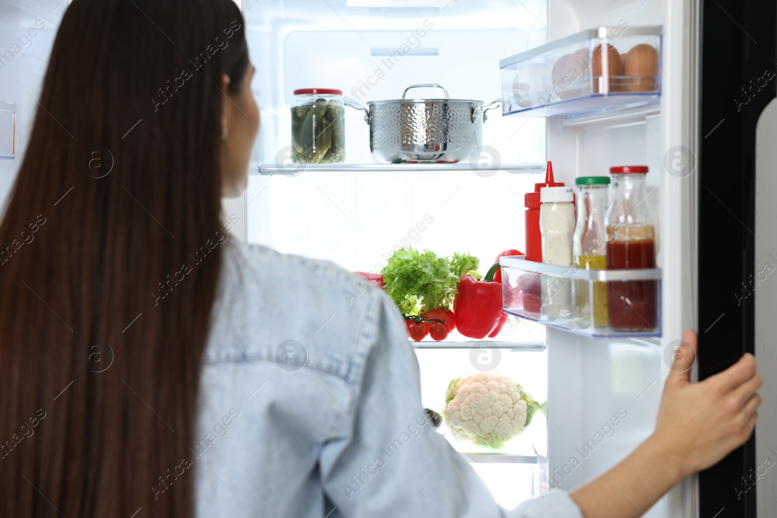 Photo of Young woman near modern refrigerator, selective focus