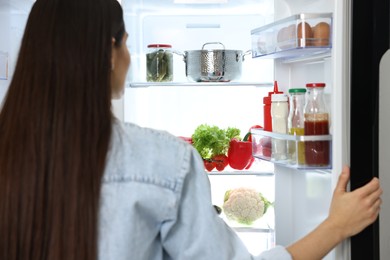 Photo of Young woman near modern refrigerator, selective focus