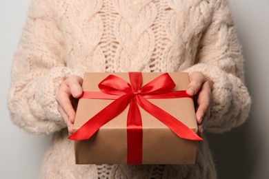 Photo of Woman holding Christmas gift box on grey background, closeup