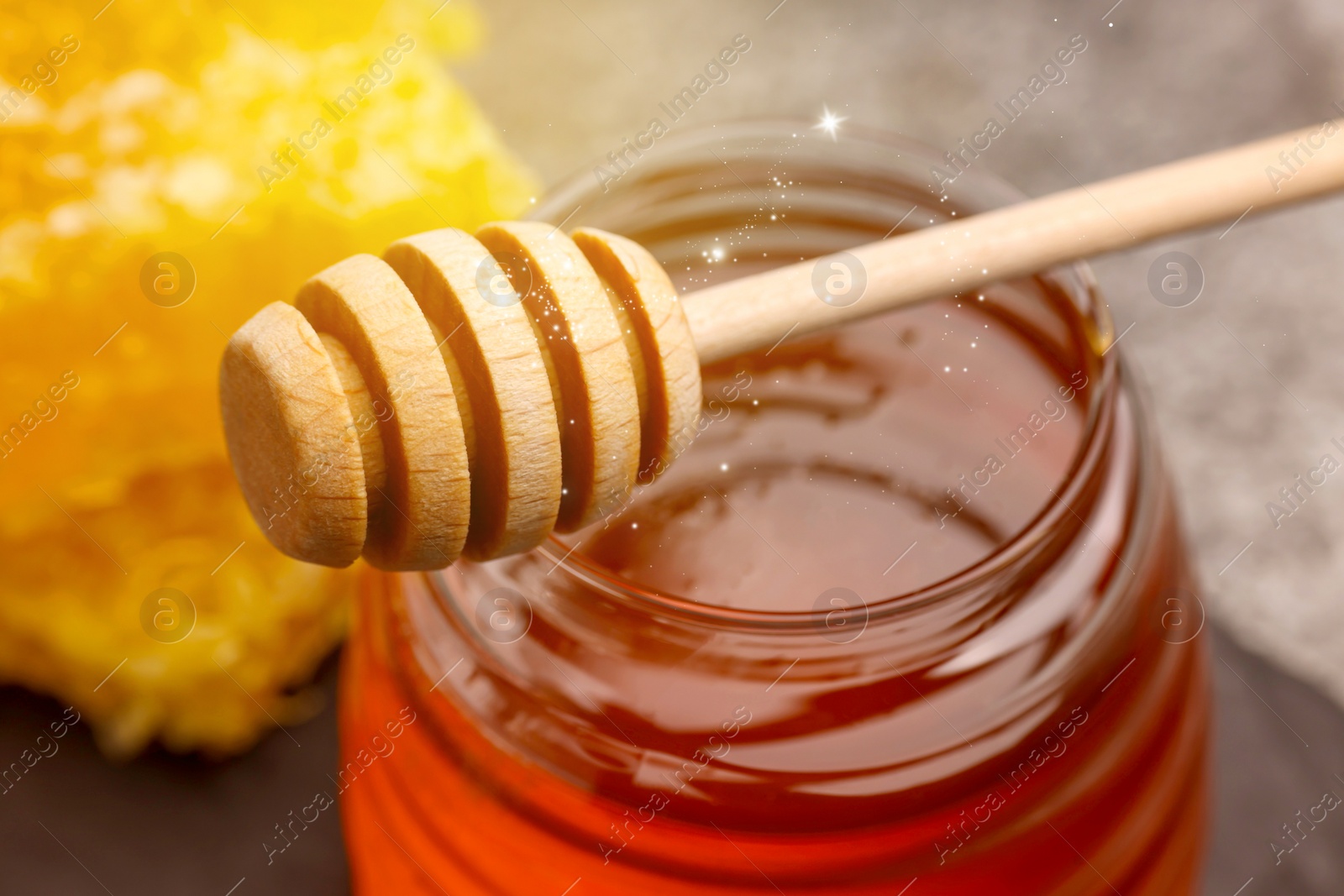 Image of Natural honey in glass jar and wooden dipper under sunlight, closeup