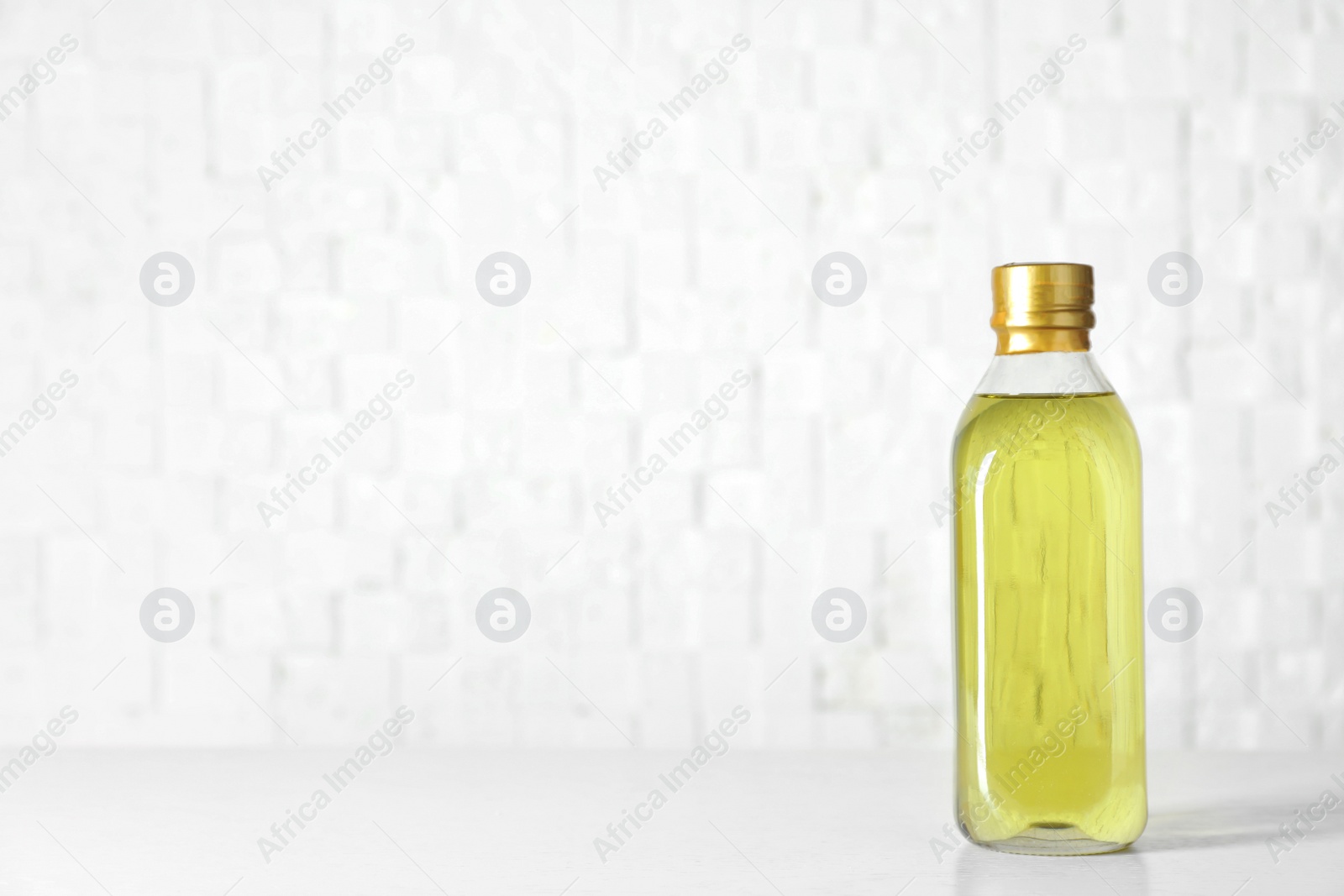 Photo of Bottle of oil on table against light background. Space for text