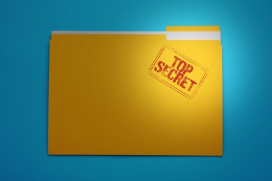 Image of Yellow file with documents and Top Secret stamp on light blue background, top view