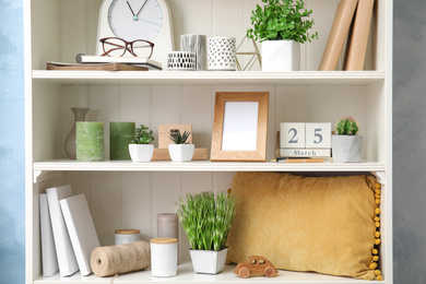 Photo of White shelving unit with plants and different decorative stuff