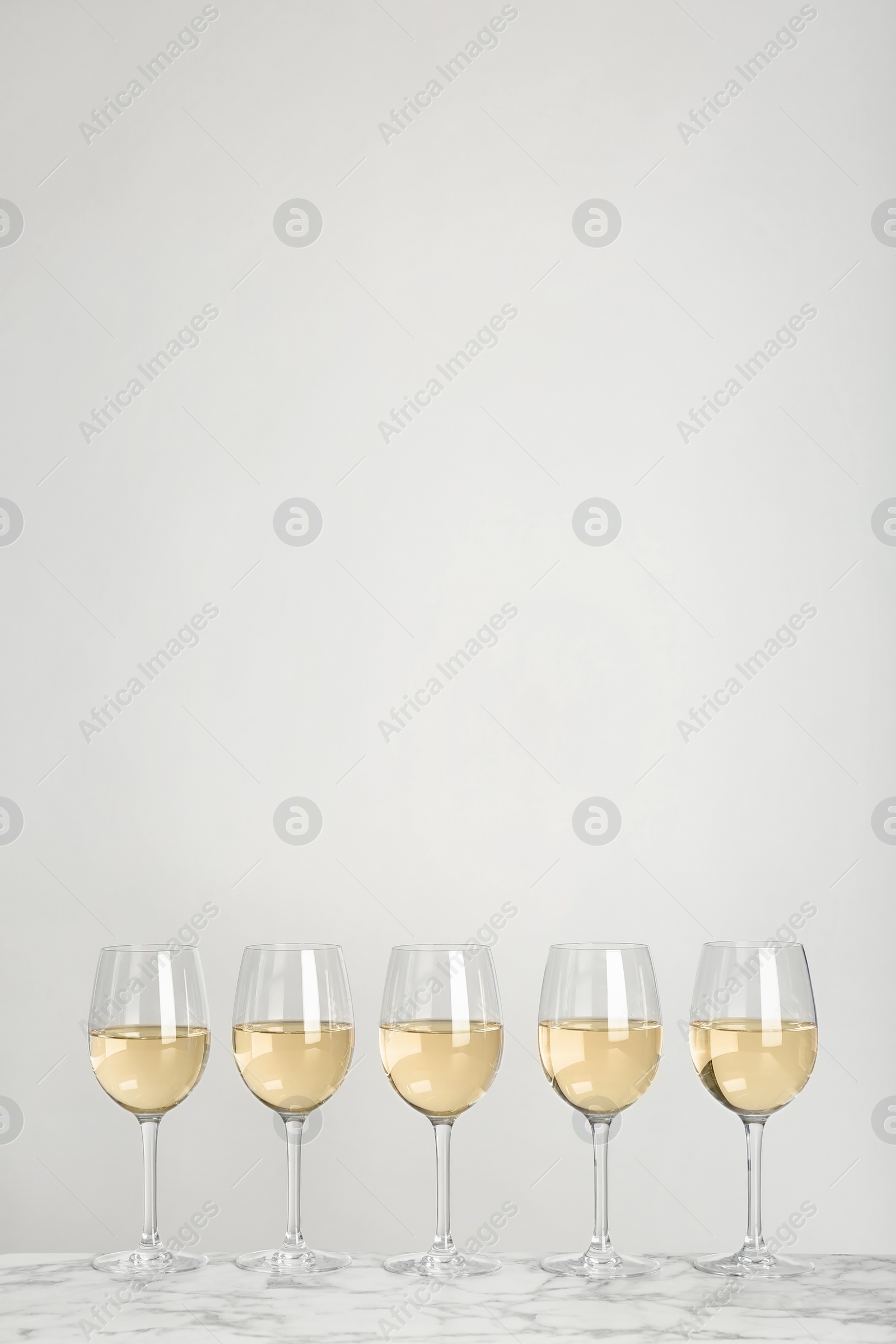 Photo of Glasses with white wine on light background