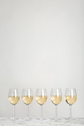 Glasses with white wine on light background