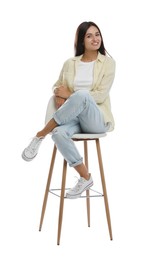 Beautiful young woman sitting on stool against white background