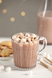 Cup of aromatic hot chocolate with marshmallows and cocoa powder on white table, closeup