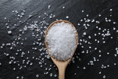 Photo of Organic white salt and spoon on black table, top view