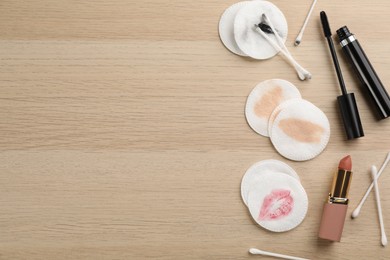 Dirty cotton pads, swabs and cosmetic products on wooden background, flat lay. Space for text