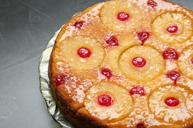 Plate with tasty pineapple cake on grey textured table, closeup. Space for text