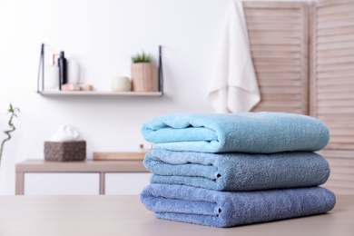 Photo of Stack of fresh towels on table in bathroom. Space for text