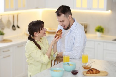 Tasty breakfast. Happy wife feeding her husband at home