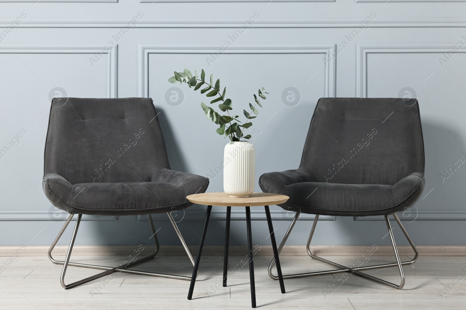 Photo of Comfortable armchairs, side table and eucalyptus indoors