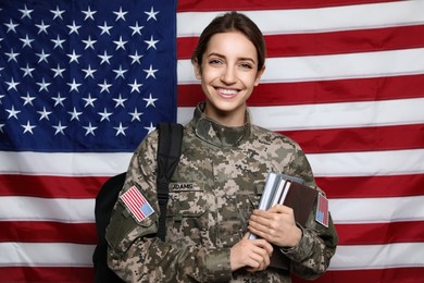 Female cadet with backpack and books against American flag. Military education