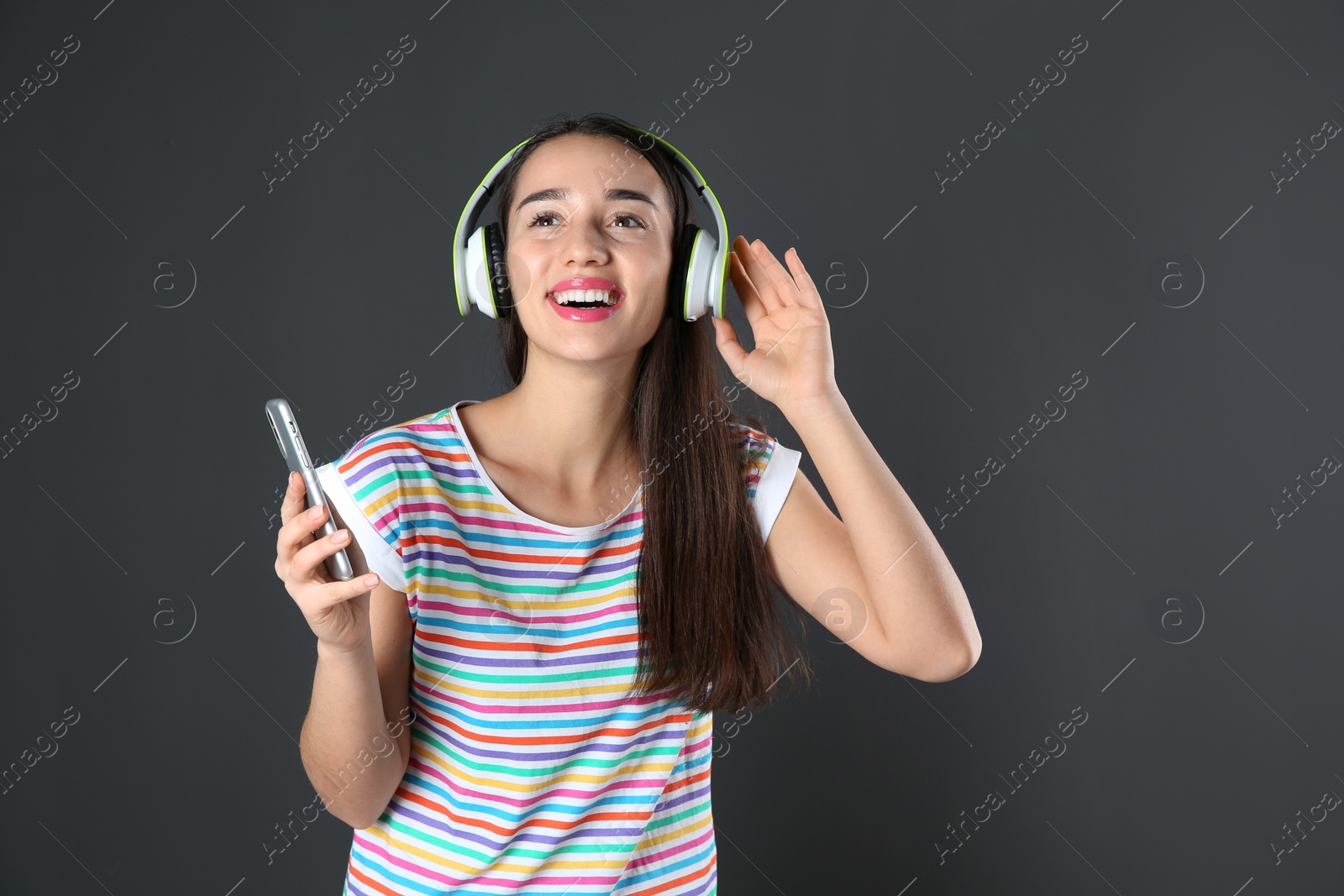 Photo of Beautiful young woman listening to music with headphones on black background