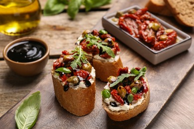 Photo of Delicious bruschettas with balsamic vinegar and toppings on wooden table