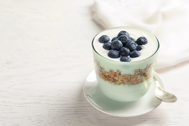 Photo of Glass with yogurt, berries and granola on table