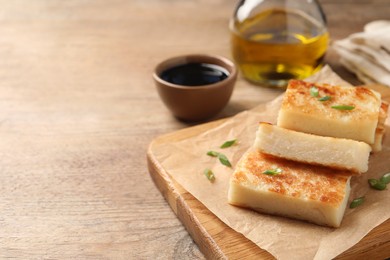 Delicious turnip cake with green onion on wooden table, space for text