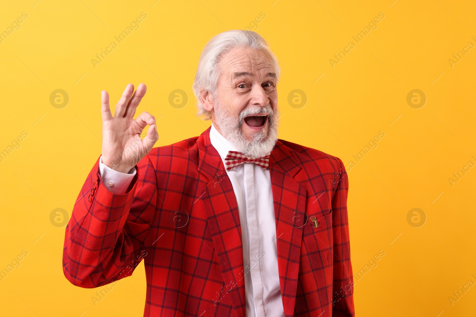 Photo of Portrait of grandpa with stylish red suit and bowtie showing ok gesture on yellow background