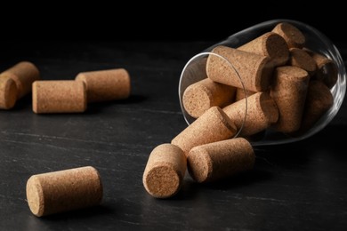 Photo of Glass with wine corks on dark table, closeup