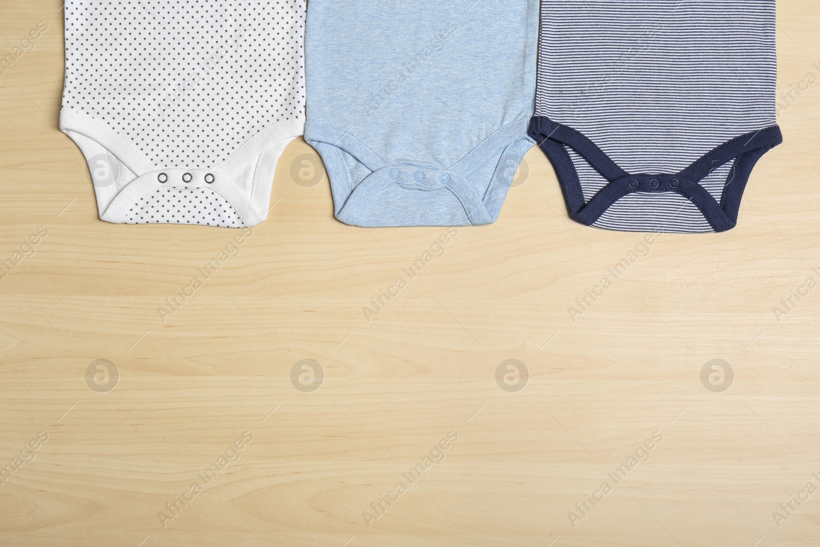 Photo of Different baby bodysuits on wooden background, top view. Space for text