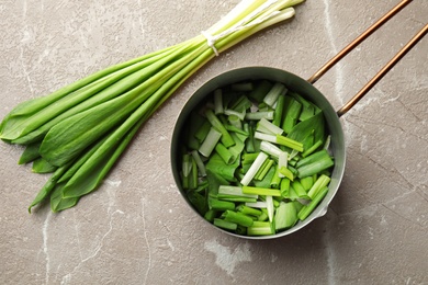 Photo of Saucepan and wild garlic or ramson on grey table, top view