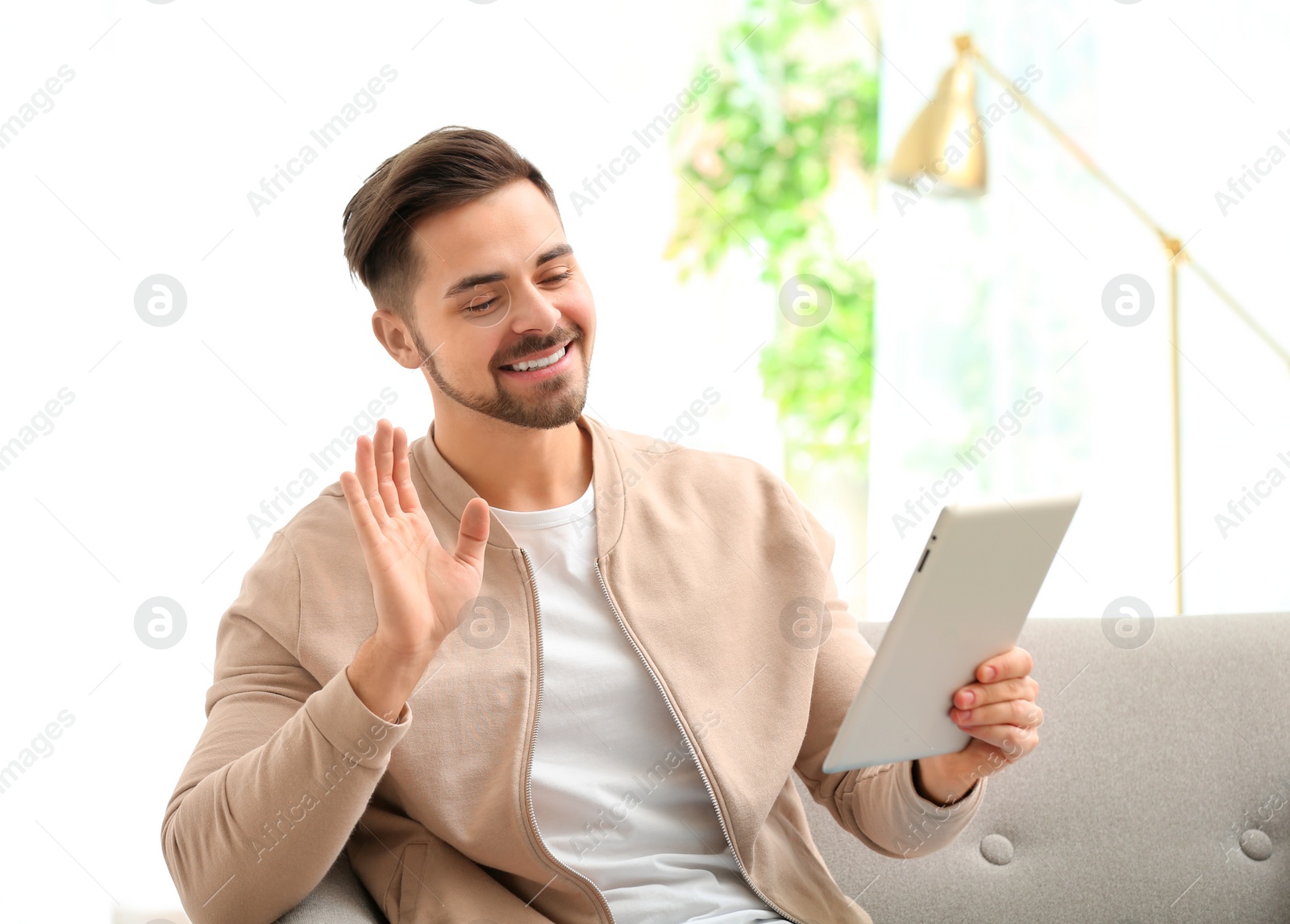 Photo of Man using tablet for video chat in living room