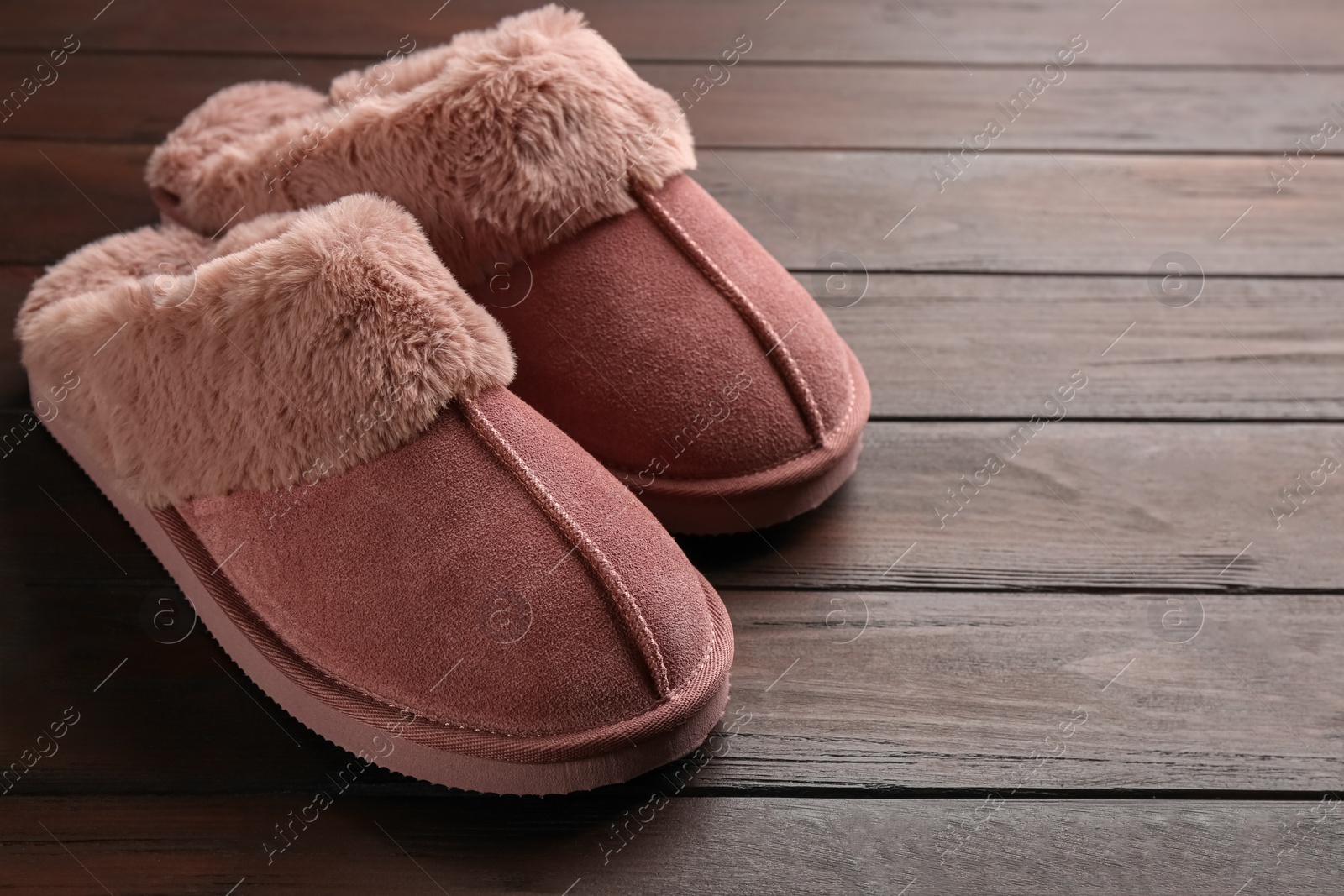 Photo of Pair of stylish soft slippers on wooden background. Space for text