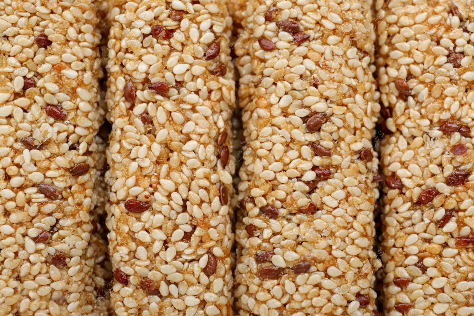 Photo of Tasty sesame seed bars as background, top view