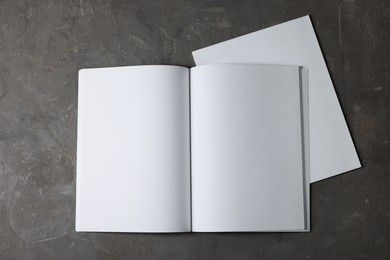 Photo of Open notebook with blank paper sheets on grey textured background, top view. Mockup for design