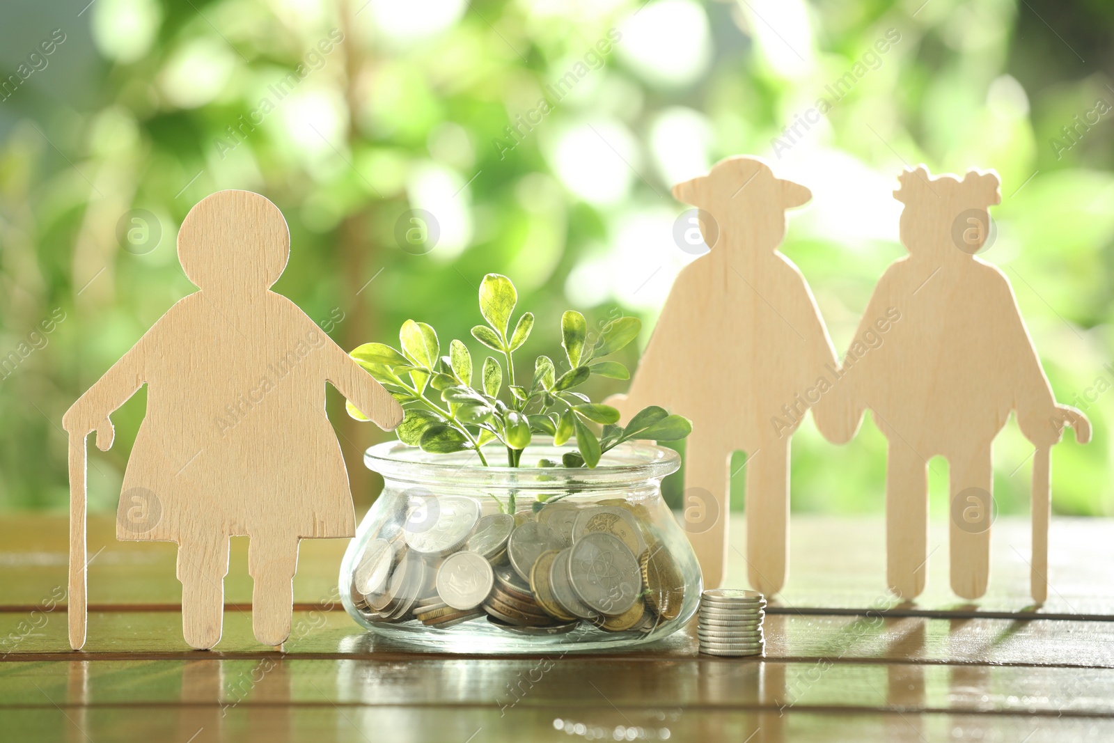 Photo of Pension savings. Figures of elderly people, coins and green twig in jar outdoors