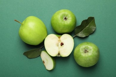 Photo of Whole, cut green apples and leaves on color background, flat lay