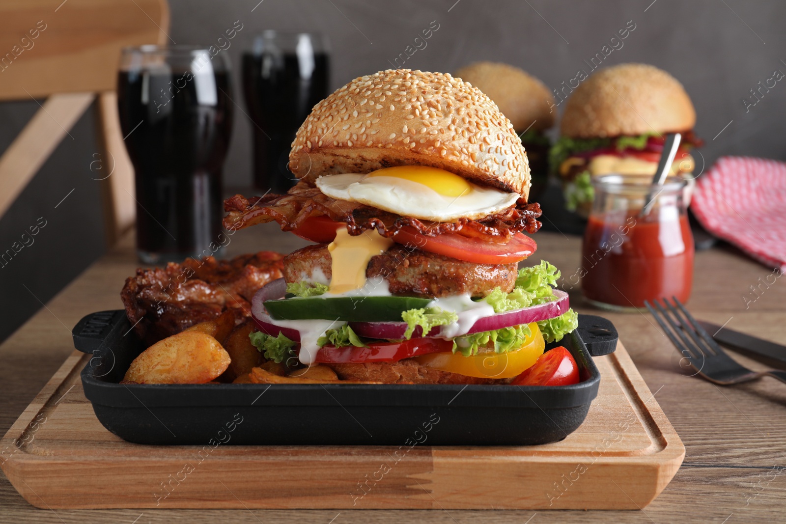 Photo of Serving pan with juicy bacon burger on wooden board